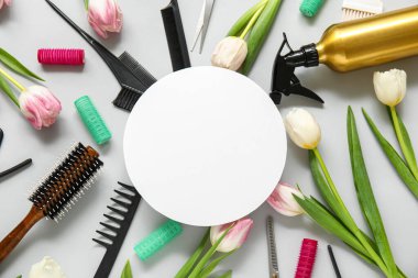 Boş kart, kuaför aletleri ve gri arka planda güzel laleler.