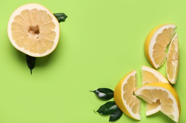 Yeşil arka planda dilimli ve yapraklı lezzetli aromalı pomelo meyvesi