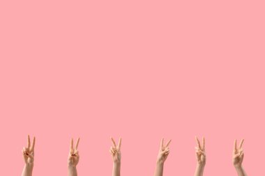 Pembe arka planda barış jestleri gösteren kadın elleri