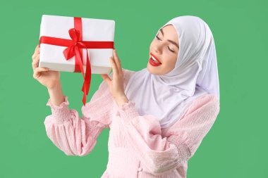 Yeşil arka planda Noel hediyesi kutusu olan güzel Müslüman kadın.