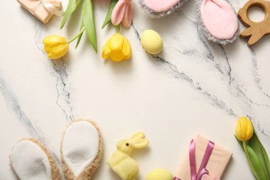 Paskalya yumurtalı tavşan kulakları, hediye kutuları ve beyaz mermer arka planda lale çiçekleri.