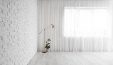 Oturma odasındaki ışık perdesinin yanındaki lamba ve bitki.