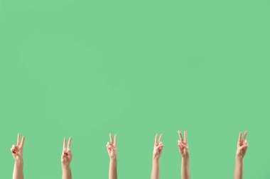 Yeşil arka planda barış jestleri gösteren kadın eller