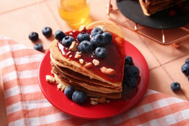 Kalp şeklinde lezzetli gözlemeler, bej kaplamalı yaban mersini ve fındıklı fındıklar, yakın plan. Sevgililer Günü kutlaması