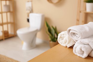 Ev bitkisi, seramik klozet ve ahşap masa üzerinde havlular olan şık bir banyo.