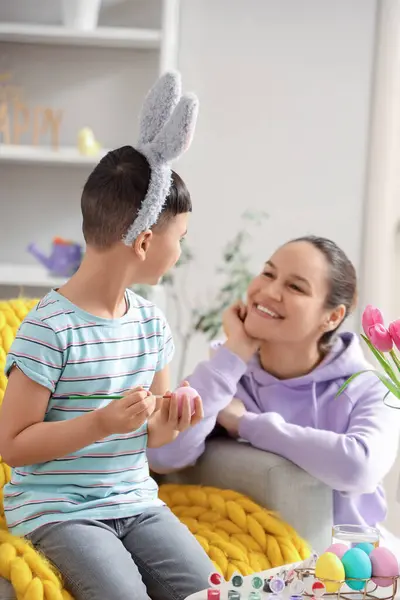Genç anne ve küçük oğlu evde paskalya yumurtası boyuyor.