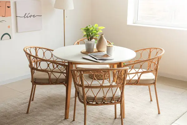 Yemek masasında bitki, vazo, bardak ve dergiler var.