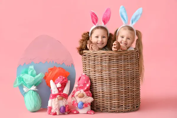 可爱的小女孩 篮子里装着巧克力复活节彩蛋 粉红的背景装饰着 — 图库照片