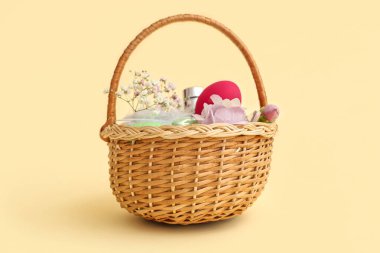 Parfümlü hasır sepet, sarı arka planda Paskalya yumurtaları ve çiçekler.