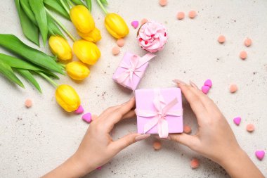 Güzel bir hediye kutusu ve arka planda laleleri olan bir kadın.