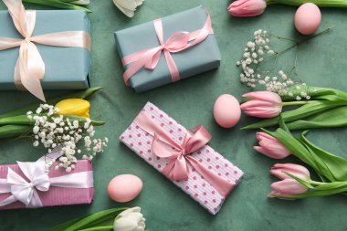 Paskalya yumurtaları hediye kutuları ve yeşil arkaplanda çiçekler.