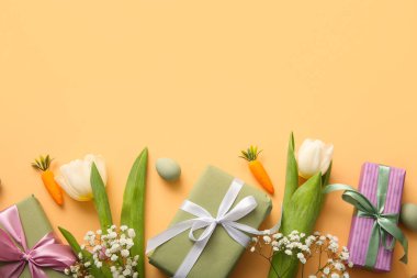 Çiçekli Paskalya yumurtaları ve turuncu arka planda hediye kutuları.