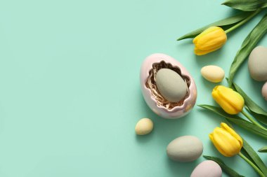 Turkuaz arka planda Paskalya yumurtaları ve lale çiçekleriyle tutucu