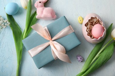 Hediye kutulu Paskalya yumurtaları ve mavi grunge arka planda tavşan.