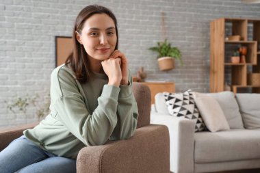 Mutlu genç kadın evde koltukta oturuyordu