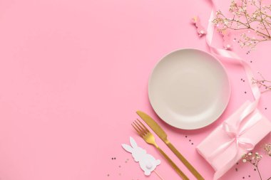 Pembe arka planda hediyeler ve yumurtalarla süslenmiş Paskalya sofrası.