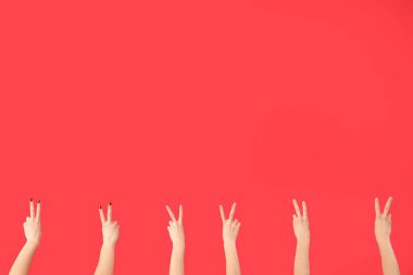 Kırmızı arka planda barış hareketlerini gösteren kadın elleri