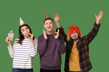 Kağıt palyaçoyla kılık değiştirmiş genç arkadaşlar ve yeşil arka planda ıslıklar. 1 Nisan kutlamaları