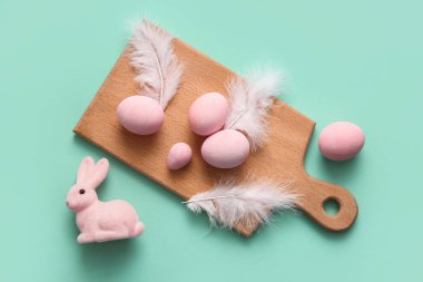 Boyanmış Paskalya yumurtaları, tüyler ve turkuaz arka planda bir tavşan olan tahta tahta tahta tahta tahta tahta.