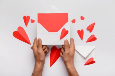 Zarflı erkek eller, boş kart ve beyaz arka planda kırmızı kağıt kalpler. Sevgililer Günü kutlaması