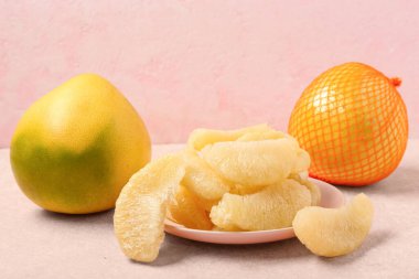 Pembe arkaplanda parçaları olan lezzetli aromalı meyve ve tabak.