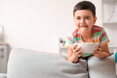 Evde bir kase mısır gevreği halkası olan sevimli küçük bir çocuk.