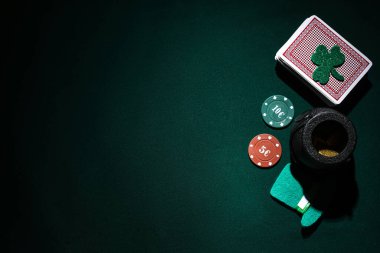 Poker fişleri, kartlar, bozuk paralar ve koyu yeşil arka planda uğurlu yoncalar. Aziz Patrick Günü kutlaması