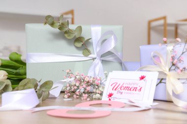 Tahta masadaki Uluslararası Kadınlar Günü için güzel hediye kutuları, çiçekler ve tebrik kartı.
