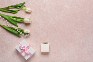 Boş defterli lale çiçekleri ve pembe grunge arkaplanlı hediye kutusu. Uluslararası Kadınlar Günü kutlamaları