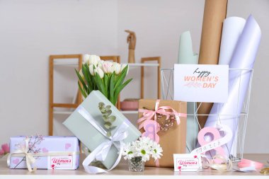 Gri duvara karşı Uluslararası Kadınlar Günü için güzel hediye kutuları, paketleme malzemeleri ve çiçekler.