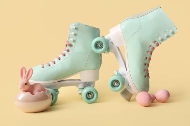 Sarı arka planda Paskalya yumurtası ve oyuncak tavşanlı klasik patenler.