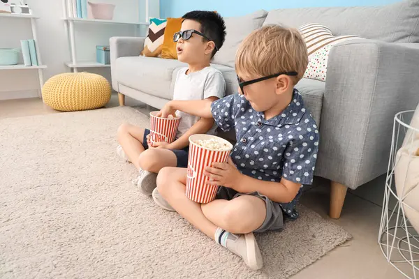 Üç boyutlu gözlüklü, patlamış mısırlı şirin çocuklar evde film izliyor.