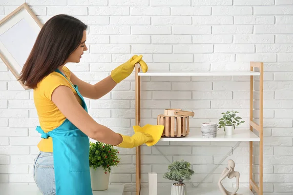 Parti sonrası oturma odasında mobilyaları temizleyen genç bir kadın.