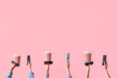 Kovalarca patlamış mısır, 3 boyutlu gözlük ve pembe arka planda televizyon kumandalı eller.