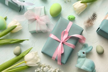 Çiçekli Paskalya yumurtaları ve mavi grunge arka planda hediye kutuları.