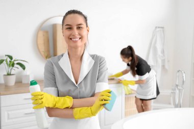 Banyoda temizlik süngeri ve deterjanı olan genç oda hizmetçisi.