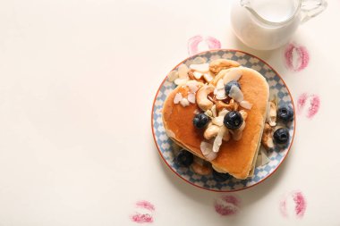 Kalp şeklinde leziz krepler ve beyaz arka planda ruj izi olan bir tabak. Sevgililer Günü kutlaması