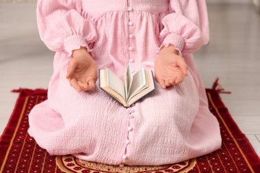 Kuran 'ı dinleyen genç Müslüman kadın evde namaz kılıyor.