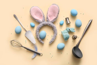 Paskalya yumurtalı tavşan kulakları ve bej arka planda pişirme aletleri.