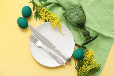 Renkli yumurtalar, yeşil peçete ve sarı arka planda mimoza ile güzel bir Paskalya sofrası.