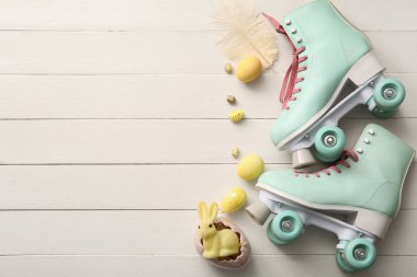 Beyaz ahşap arka planda Paskalya yumurtası ve oyuncak tavşanlı klasik patenler.