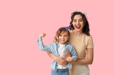 Güzel kadın ve kızı pembe arka planda kaslarını gösteriyorlar.