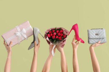 Lale buketi, hediye kutusu ve yeşil arka planda yüksek topuklu ayakkabıları olan kadın elleri. Uluslararası Kadınlar Günü için Alışveriş