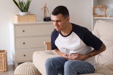 Evde karın ağrısı çeken genç bir adam.