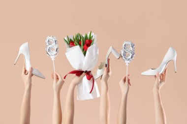 Kırmızı lale buketi, balonlar ve bej arka planda yüksek topuklu ayakkabılar olan kadın elleri. Uluslararası Kadınlar Günü için Alışveriş