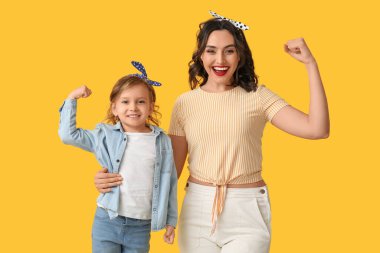 Güzel bir poster kadını ve kızı sarı arka planda kaslarını gösteriyor.