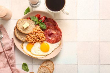 Lezzetli İngiliz kahvaltısı ve beyaz fayanslı bir fincan kahve.