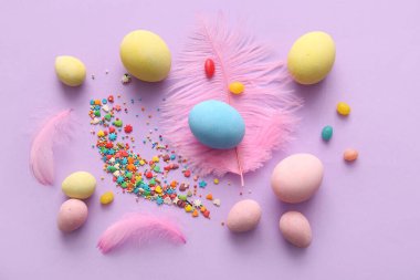 Mor arka planda tüyleri olan boyalı Paskalya yumurtaları.