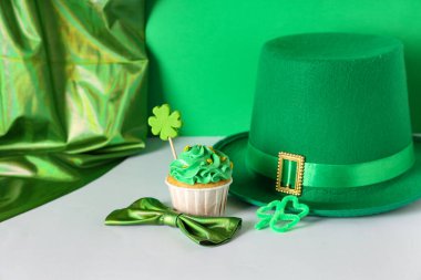 Lezzetli kek, leprikon şapkalı ve papyonlu Aziz Patrick Günü için yeşil arka planda beyaz masada.