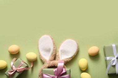 Paskalya yumurtaları ve yeşil arka planda hediye kutuları olan tavşan kulakları.